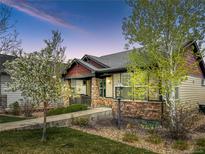 Charming single-Gathering home featuring a covered front porch, stone accents, and well-maintained landscaping at dusk at 19834 W 56Th Pl, Golden, CO 80403