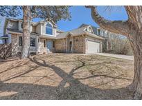 Charming two-story home featuring a brick facade, a blue front door, and a two-car garage at 6651 Yale Dr, Highlands Ranch, CO 80130