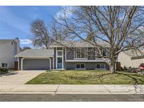 Charming gray two-story home with a well-maintained lawn, mature trees, attached garage and inviting blue front door at 145 S Buchanan Ave, Louisville, CO 80027