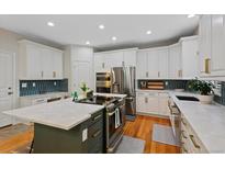 A spacious kitchen featuring stainless steel appliances, a center island, and white cabinetry at 12054 E Lake Cir, Greenwood Village, CO 80111