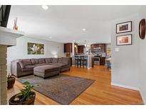 Open concept living room featuring a large sofa, hardwood floors, and updated kitchen at 2582 Beech Ct, Golden, CO 80401