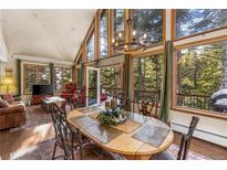 Dining room with large windows overlooking the forest and a stylish chandelier above a wooden table at 609 Brook Dr, Idaho Springs, CO 80452