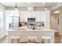 Bright kitchen with stainless steel appliances, white cabinets, and a center island with seating at 1208 Quitman St # 305, Denver, CO 80204