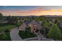 Stunning aerial view of a two-story home with landscaped yard against the backdrop of a colorful sunset and mountain range at 9375 Webster Way, Westminster, CO 80021