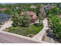 Beautiful home exterior with lush landscaping, mature trees, and a spacious front lawn at 8707 Windhaven Dr, Parker, CO 80134