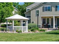 Charming townhome exterior with a well-manicured lawn, white gazebo, and inviting front porch at 930 Button Rock Dr # 28, Longmont, CO 80504