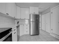 Modern white kitchen with stainless steel appliances and tile flooring at 155 S Sable Blvd # S26, Aurora, CO 80012