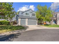 Charming gray two-story home featuring a two-car garage and well-maintained front lawn with mature trees at 10915 Acadia Ln, Parker, CO 80138