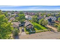 Charming home features a well-manicured lawn and inviting porch with a red door and blue chairs at 5614 Yarrow St, Arvada, CO 80002