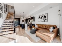 Open-concept living room featuring modern decor, hardwood floors, and a stylish kitchen with black cabinets at 2602 W 24Th Ave # 6, Denver, CO 80211