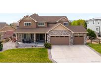 Charming two-story home featuring stone accents, a spacious driveway, and a welcoming front porch at 17378 W 78Th Dr, Arvada, CO 80007