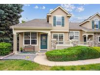 Charming home featuring a covered front porch, green door, and well-manicured landscaping at 10166 Grove Loop # D, Westminster, CO 80031