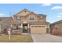 Charming two-story home features a two car garage, stone accents, and manicured lawn at 9968 E Kansas Ave, Aurora, CO 80247