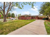 Charming red brick home featuring a well-manicured lawn and a convenient covered carport at 2201 Lima St, Aurora, CO 80010