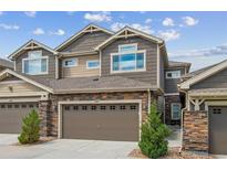 Beautiful townhouse showcasing a stone and shingle exterior, two-car garage, and well-maintained landscaping at 15079 E Poundstone Pl, Aurora, CO 80015