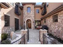 Charming stone front entrance with courtyard, wrought iron gate, and cozy seating area at 651 Ruby Trust Dr, Castle Rock, CO 80108