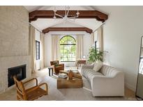 Inviting living room boasts vaulted ceilings, exposed beams, fireplace and a large arched window at 5800 E 6Th Avenue Pkwy, Denver, CO 80220