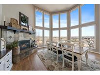 Bright dining area with a stone fireplace, large windows, and hardwood floors create an inviting and elegant space at 12007 W 54Th Dr, Arvada, CO 80002