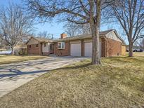 Brick exterior with a well-maintained lawn and a wide driveway leading to a two-car garage at 6580 W Nevada Pl, Lakewood, CO 80226