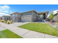 Charming home with a well-manicured lawn, stone accents, and an attached two-car garage at 1962 Canyonpoint Ln, Castle Pines, CO 80108