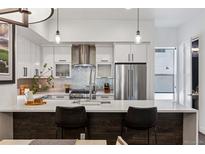 Bright kitchen with white cabinets, stainless appliances, stylish backsplash, and large island with seating at 3036 Wilson Ct # 5, Denver, CO 80205