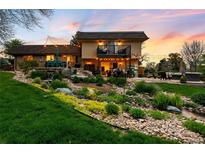 Beautifully landscaped backyard featuring a waterfall, lush greenery, and a cozy outdoor seating area at 5020 W Quarles Dr, Littleton, CO 80128