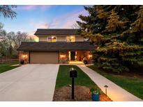 Charming two-story home featuring a well-manicured front yard and stone accents at dusk at 5020 W Quarles Dr, Littleton, CO 80128