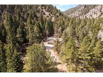 Stunning aerial view of a mountain home nestled among lush trees and surrounded by scenic mountain views at 993 Fall River Rd, Idaho Springs, CO 80452