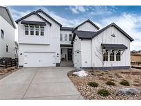 Beautiful two-story home with white siding, black trim, a two-car garage, and rock landscaping at 3898 Descent St, Castle Rock, CO 80108