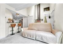 Bright living room with white walls, fireplace, and view of the kitchen bar at 8701 Huron St # 211, Thornton, CO 80260