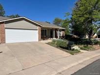 Charming single-story home featuring a manicured lawn, brick accents, and an attached two-car garage at 4063 S Cathay Ct, Aurora, CO 80013