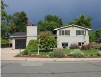 Charming two-story home featuring manicured landscaping and a black two car garage at 6864 Balsam St, Arvada, CO 80004
