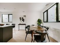 Modern dining room features wood floors, table with black chairs, and abundant natural light from large windows at 1601 Park Ave # 214, Denver, CO 80218