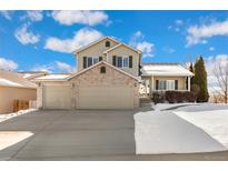 Two-story house with three-car garage, brick facade, and snow-covered landscaping at 10890 W Belmont Ave, Littleton, CO 80127