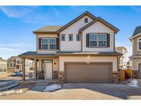 Two-story house with beige and brown siding, a two-car garage, and a paved driveway at 16142 E 111Th Dr, Commerce City, CO 80022