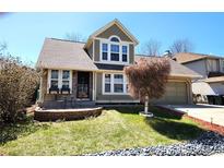 Charming two-story home boasts a well-manicured lawn, complemented by a cute weeping cherry tree and seating area at 13474 W 65Th Dr, Arvada, CO 80004