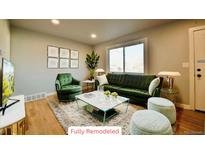 Bright living room showcasing stylish green furniture, modern decor, and gleaming hardwood floors at 1705 S Yuma St, Denver, CO 80223