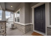 Charming front porch with stone accents, a sitting area, and a welcoming black front door at 3008 Blithe Pt, Castle Rock, CO 80108