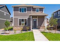Two-story home with stone accents, gray siding, a well-manicured lawn and walkway to the front door at 28630 E 8Th St, Watkins, CO 80137