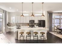 Stylish kitchen with island seating, pendant lighting, and modern appliances in an open floor plan at 2572 Iola St, Aurora, CO 80010