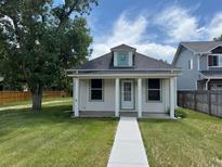 Charming single-story home with white siding, a covered porch, and a well-maintained front lawn at 10630 W 46Th Ave, Wheat Ridge, CO 80033