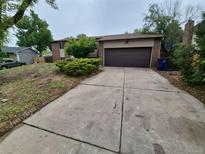 View of the house with a driveway and a garage and some landscaping at 3246 S Nucla St, Aurora, CO 80013