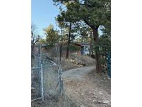 Rustic home exterior nestled amongst mature trees, featuring a gated entrance and gravel driveway at 433 Gunn Ave, Berthoud, CO 80513