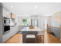 Bright, open kitchen boasts stainless appliances, large island with seating, and gorgeous cabinets at 11223 W 29Th Ave, Lakewood, CO 80215