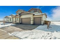 Two-story home featuring a two car garage and a lawn covered with snow at 5784 Farmstead Pl, Mead, CO 80504