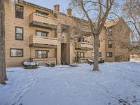 Snow covered exterior of condo building with trees and landscaping at 400 Zang St # 1-105, Lakewood, CO 80228