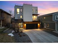 Modern three-story home with a rooftop deck and stone and white stucco facade with a two car garage at 9742 Fairwood St, Littleton, CO 80125