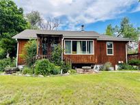 Charming single-story home featuring wood siding and a covered front porch with lush landscaping at 8211 Rocky Mountain Dr, Lakewood, CO 80214