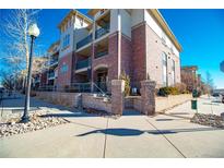 Attractive three-story building with brick accents, balconies, and well-maintained landscaping at 3872 S Dallas St # 7-107, Aurora, CO 80014