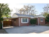 Charming brick home features a carport, well-maintained landscaping, and a spacious driveway at 2211 Quebec St, Denver, CO 80207